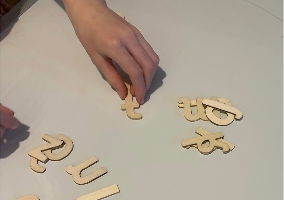 Hands arranging wooden letter tiles